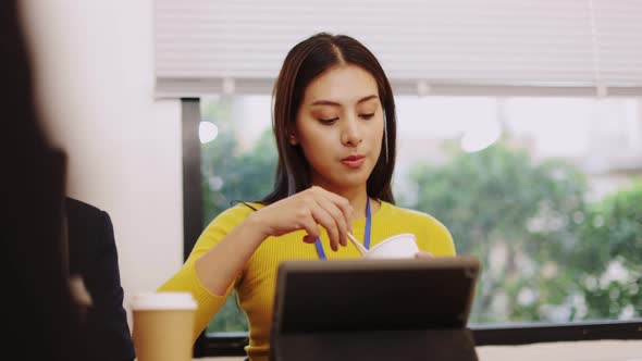 Asia freelance  business woman eating instant noodles while working on laptop