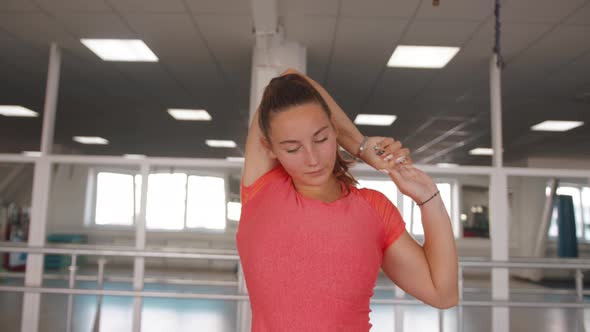 Beautiful Young Girl Recovering From Strength Training in the Gym and Doing Triceps Stretch