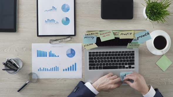 Motivated Businessman Writing Idea on Paper and Sticking It on Laptop Screen