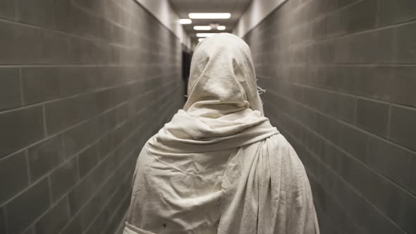 Jesus In White Robe Walks Through A Prison Hallway