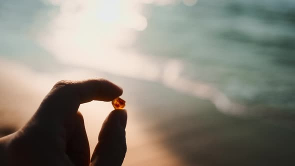 Shot of Woman's Hand Holding A Beautiful Amber Towards The Coast