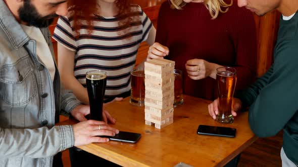 Group of fiends playing jenga while having beer 4k