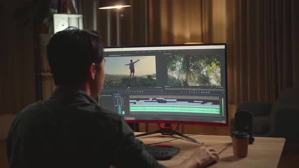 Asian Male Video Editor Works With Footage And Sound On His Personal Computer