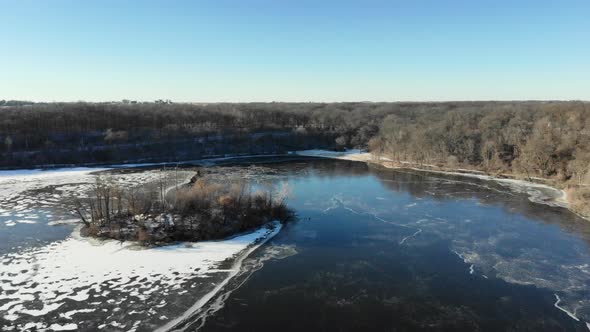 Drone video flying over a partially frozen lake in the middle of winter