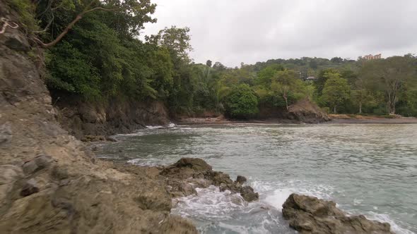 Low backwards drone flight next to the rocky shore at Costa Rica's central pacific coast.