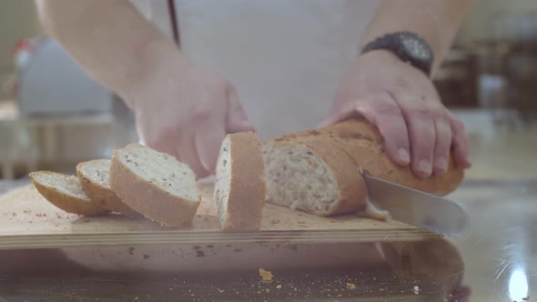 Baker is Cutting Baked Dutch Bread with Raisins and Dried Apricots with Knife