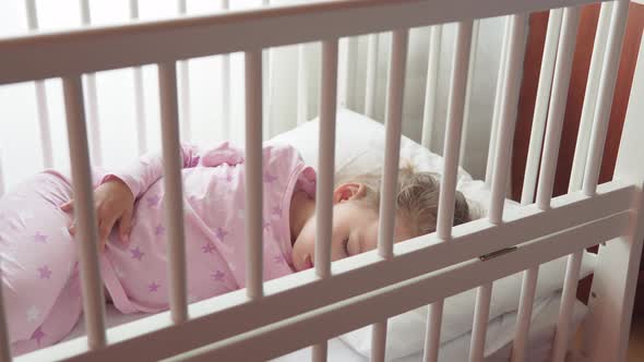 Close Up Authentic Cute Caucasian Little Preschool Child Girl Sleep Sweetly in White Crib on Pajama