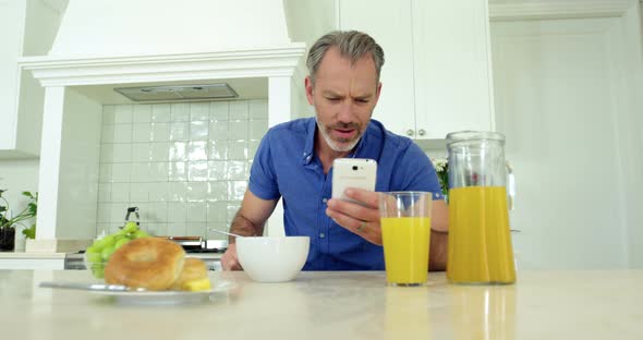 Man using mobile phone while having breakfast on dining table