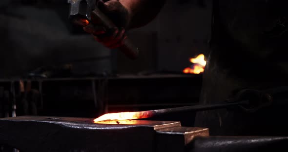 Mid-section of blacksmith working on a iron rod