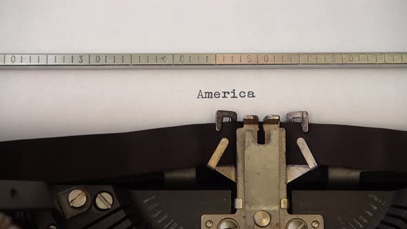 Typing word America on retro typewriter. Close up.