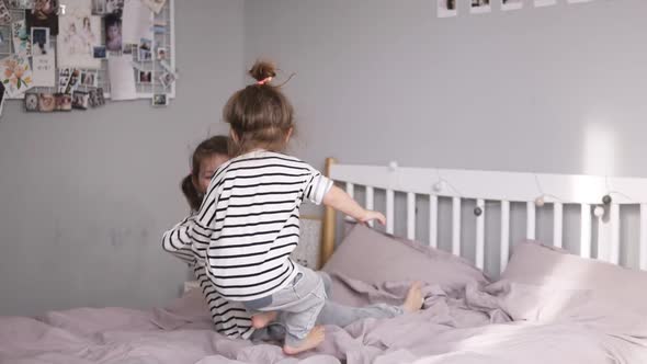 Two Little Sisters are Jumping on a Bed and Falling on It