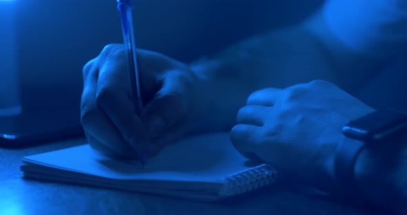 Young Barman Checking Inventory Taking Notes with Pen and Notebook Thoughtful in Nightclub in Neon