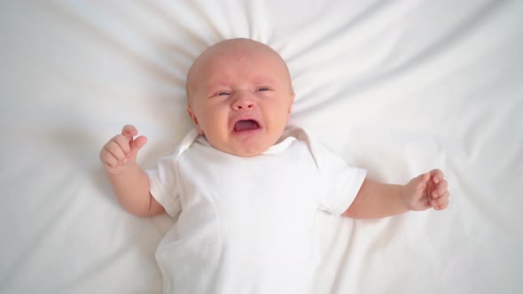 a Newborn Baby Cries on a White Sheet