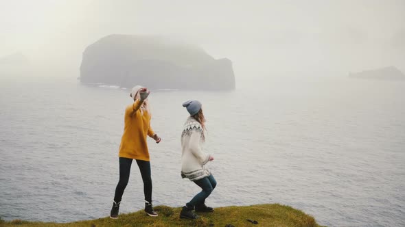 Two Happy Woman Dancing on the Shore of the Sea in Iceland, Cheerful Tourists Exploring