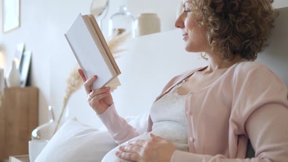 Happy Pregnant Female Resting And Reading A Book At Home