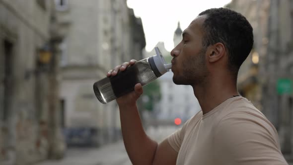 Side View African American Runner Drinking Water From the Sport Bottle After the Scamper