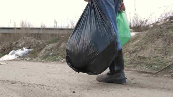 Male Legs in Boots Walking at Garbage Dump