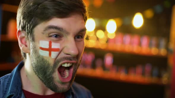 Joyful English Football Fan With Flag on Cheek Making Yes Gesture, Team Winning