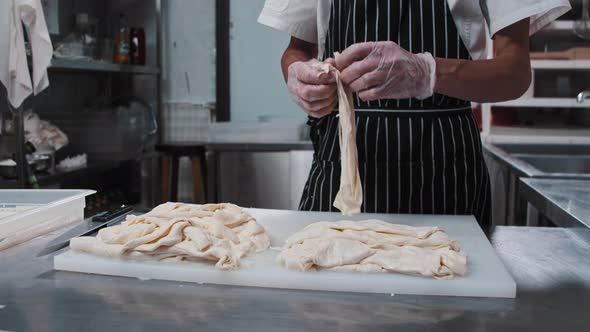 Pieces of Stretching Cheese on a Board and a Man Stretches It Into Slices