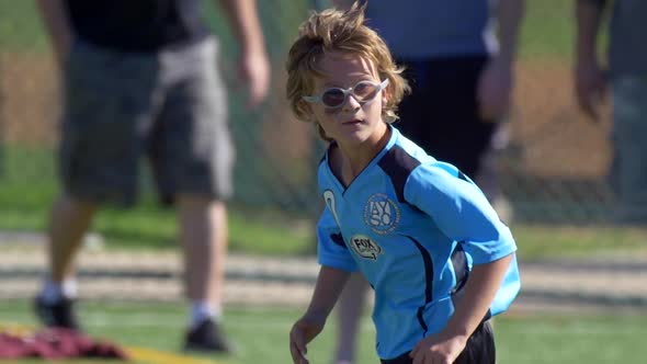 Details of a ball and boys legs playing youth soccer football on a turf field.