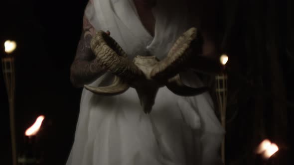 Woman Lifting Goat'S Skull In Dark Candlelit Forest