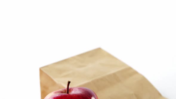 Brown paper bag and apple on white background