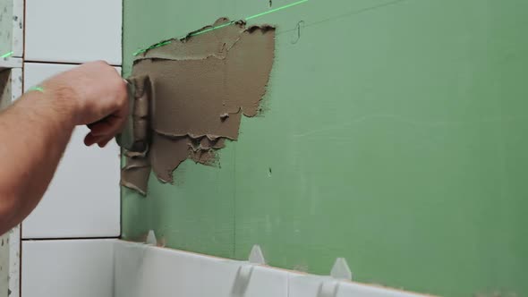 Applying Tile Adhesive to the Bathroom Wall By the Hands of an Unrecognizable Person Slow Motion