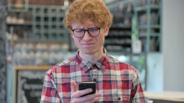 Young Redhead Man Reacting To Failure on Smartphone 