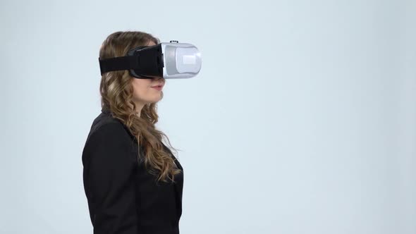 VR Concept. Woman with Virtual Reality Goggles on Gray Background, Slow Motion