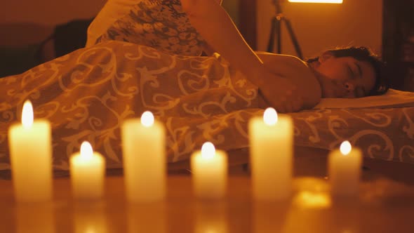 Mixed Race Ecuadorian Woman Enjoying Body Massage in Spa Salon with Candle Light