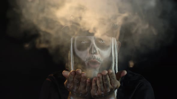 Scary Man in Thematic Carnival Costume of Halloween Skeleton Making Fly Air Kiss with Smoke