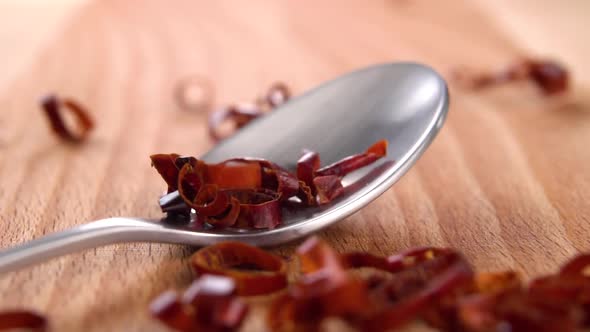 Red hot chili red cayenne pepper. Falling pieces of paprika seasoning into a spoon