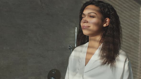 Young Positive African American Woman Wearing Bathrobe Enjoying Sunlight at Bathroom Coming to