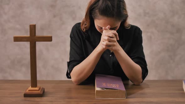 A young Asian Christian woman praying to Jesus Christ in a church.