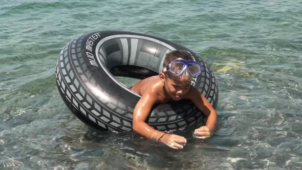 Caucasian four years old child, enjoying the sea with inflatable ring aid, slow motion medium shot