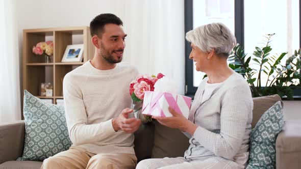 Son Giving Present and Flowers To Senior Mother