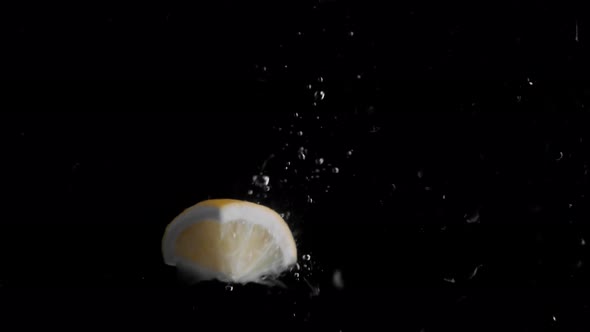 Lemon Piece Falling into Water Super Slowmotion, Black Background, lots of Air Bubbles, 4k240fps