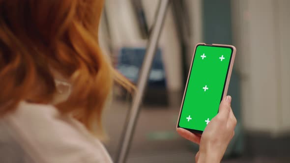 Woman hands on green screen phone watching news on a train.
