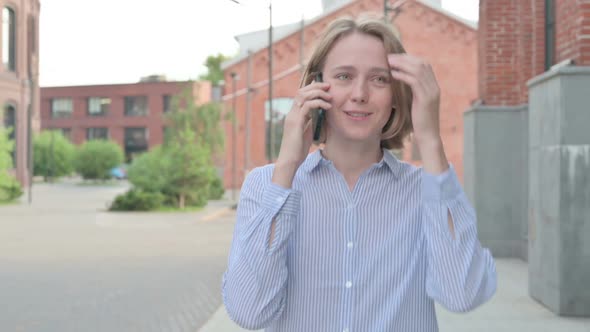 Woman Attending Phone Call While Walking in Street