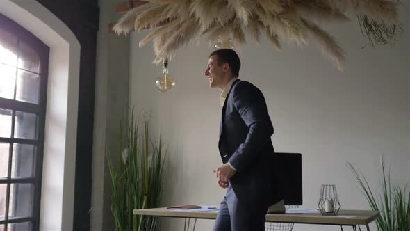 happy man in business suit dancing in office