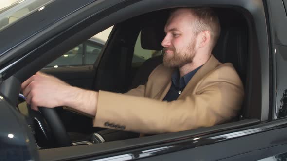 Young Attractive Man Sits in Cabin of Car.