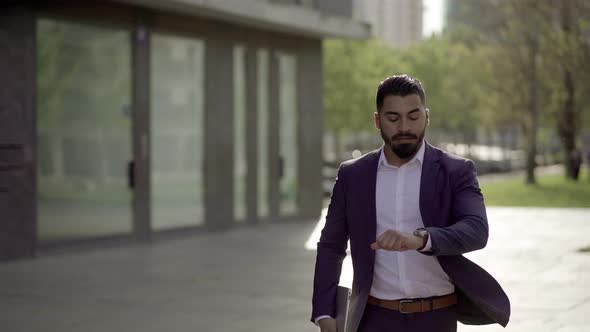 Serious Businessman with Laptop Running on Street