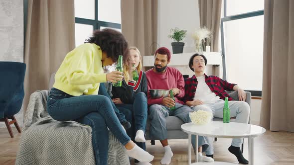 Multiethnical Young and Cheerful Men and Women Watching Comedy Movie on TV Together in the Loft