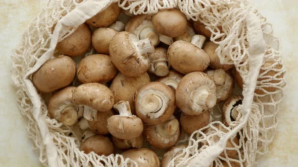 Young Fresh Champignons in a Ecological Zero-waste Net Bag Placed on Beige Background