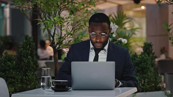 Busy African American Employee Wearing Eyeglasses Working on Laptop During Break Sitting at Outdoor