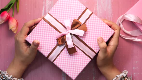 Top View of Women Hand Holding Pink Color Gist Box 