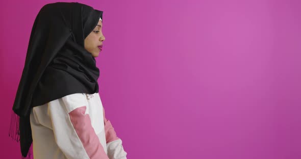 Muslim Woman in Hijab with Dumbbells Doing Exercises Over Color Background
