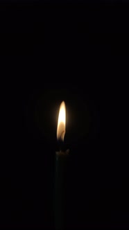 Burning candle goes out on a black background. Vertical video.