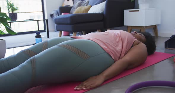 African american female plus size lying on exercise mat working out