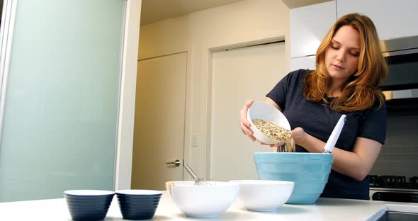 Woman adding ingredients to bowl for baking